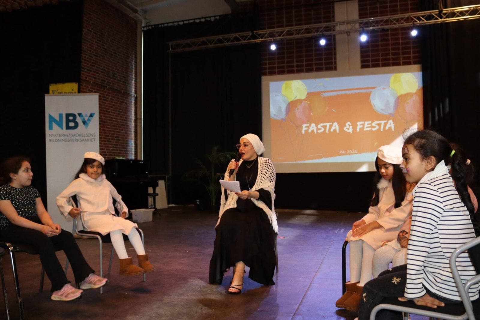 المسرح مع الأطفال وخلفهم شعار البرنامج «Fasta & Festa»
