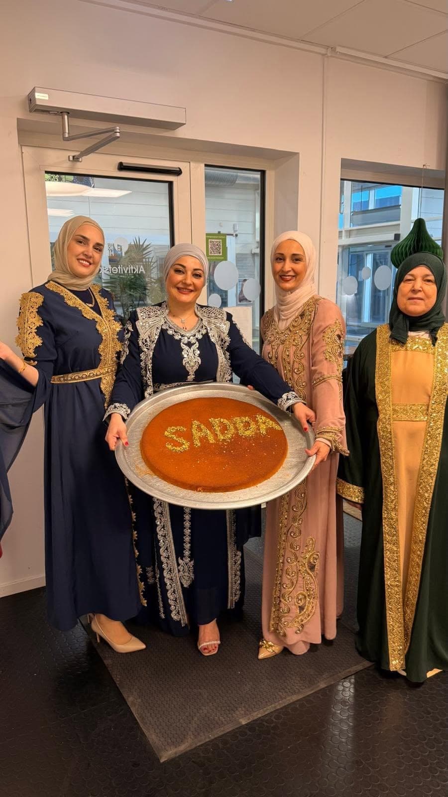 أربع من المشاركات يحملن الكنافة وقد كُتب عليها SADDA بالفستق