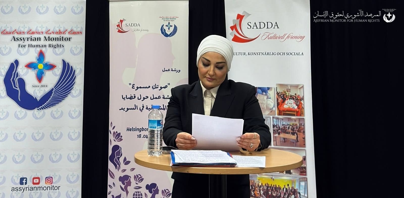 إلقاء الكلمة الافتتاحية إلى طاولة أمام راية جمعية صدى